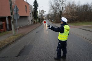 Policjantka daje sygnał tarczą do zatrzymania auta