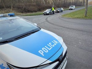 Na zdjęciu radiowóz policyjny oraz policjant badający trzeźwość kierujących na drodze.