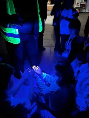 Na zdjęciu technik kryminalistyki pokazuje dzieciom jak działa lampa UV
